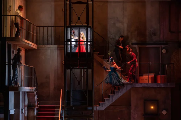 Zerlina (Samantha Gaul) und Don Giovanni (Jonathan Michie) im Aufzug, daneben Mitglieder des Ensembles sowie der Komparserie der Oper Leipzig