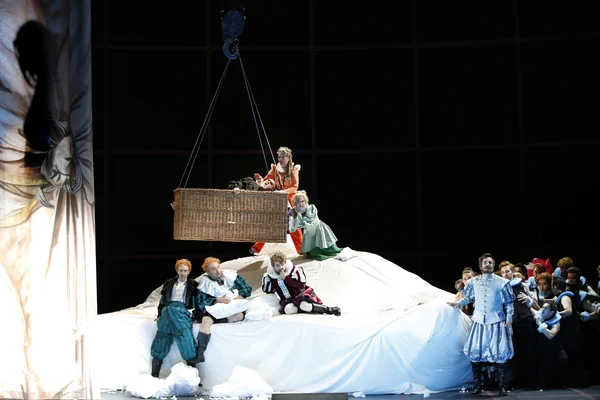 Sir John Falstaff (Lucio Gallo) oben im Korb, daneben: Mrs. Quickly (Ulrike Schneider) und Mrs. Meg Page (Maya Gour), darunter von links  Bardolph (Daniel Arnaldos), Pistola (Peter Dolinšek) und Dr. Cajus (Paul Kaufmann). Auf der rechten Seite steht Ford (Mathias Hausmann) -  dahinter Chor und Komparserie der Oper Leipzig